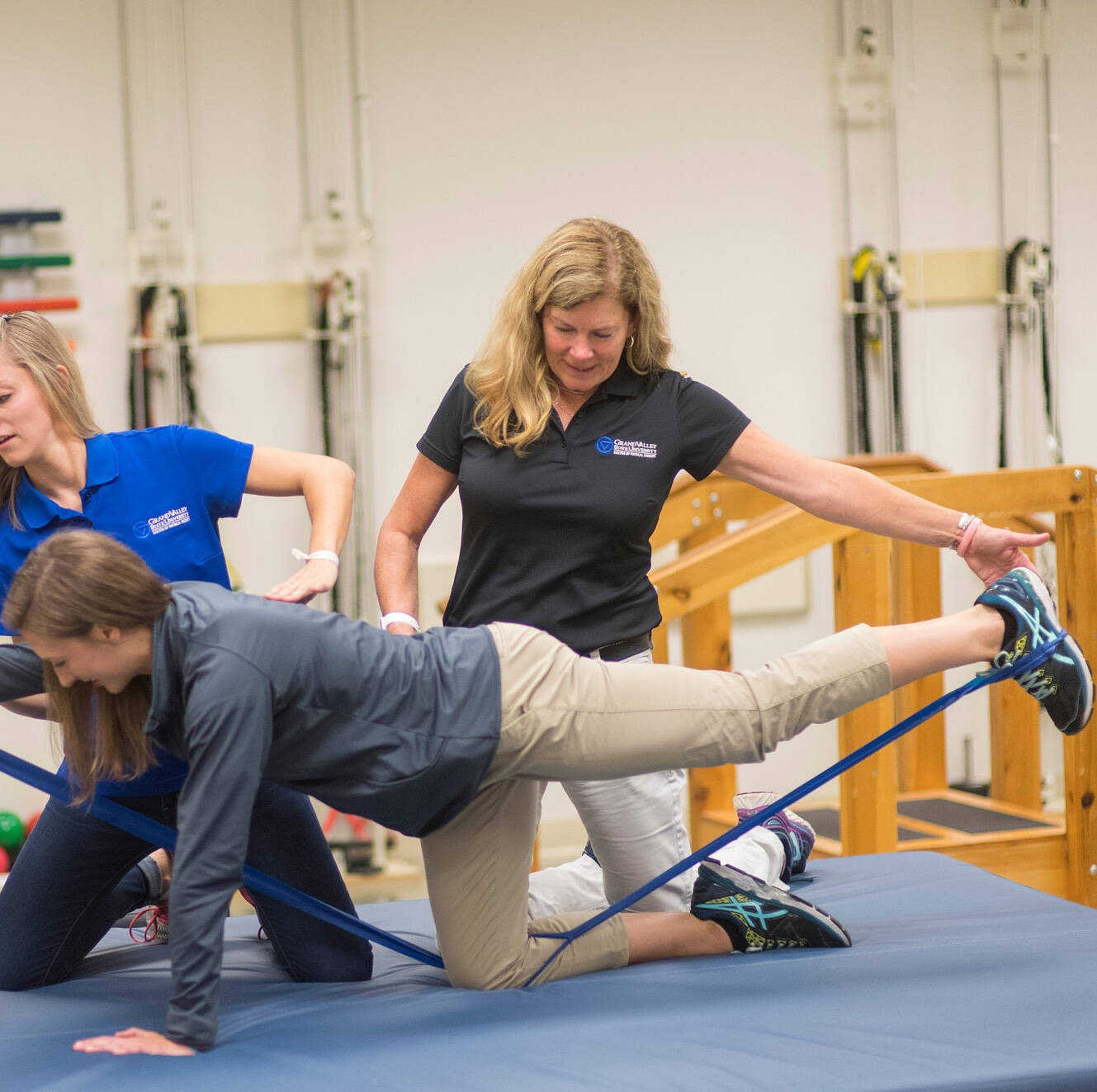 Physical therapist kneeling and working with patient who is on all fours, reaching out with right arm and left leg
